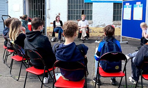 Das Foto zeigt eine Gruppe Jugendlicher bei einem Workshop auf dem Hof der Gedenkstätte Zuchthaus Cottbus.